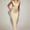 Robe longue Hivera en satin à encolure bateau et dos torsadé, couleur champagne Robe longue Hivera en satin à encolure bateau et dos torsadé, couleur champagne